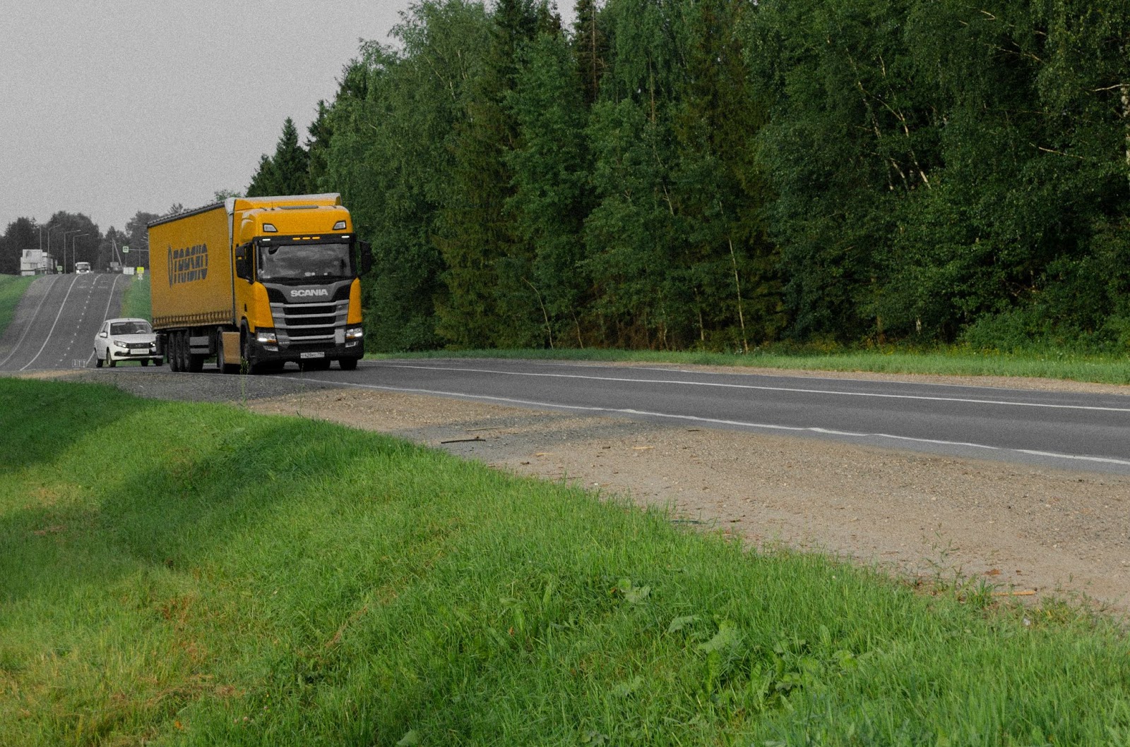 Желтый грузовик SCANIA едет по дороге